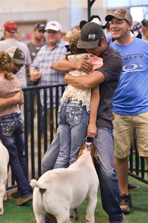 A brother hugs his sister after she wins grand champion goat at the Weld County Fair.